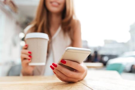 graphicstock-cropped-image-of-a-young-woman-typing-message-on-smartphone-and-drinking-cup-of-coffee-in-cafe_buk_ujrhl-1